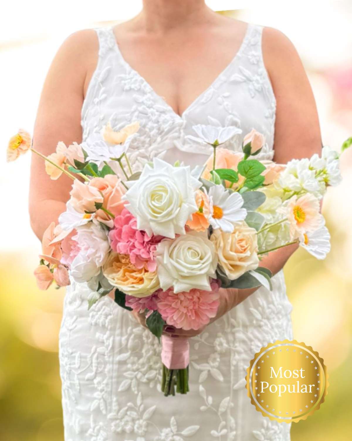 Bride holding an artificial flower bridal bouquet featuring white artificial roses, blush artificial peonies, apricot artificial tulips, peach artificial Austin roses, pink artificial hydrangeas, cream artificial tea roses, and white artificial cosmos — from My Faux Florist Canada.