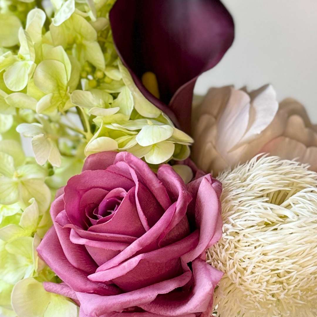 Close up of a realistic artificial flower bouquet featuring pale green artificial hydrangeas, mauve artificial roses, blush artificial peonies, white artificial allium, and deep wine artificial calla lilies — from My Faux Florist Canada.