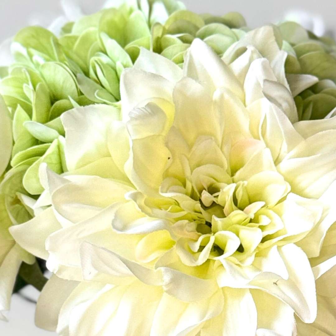 close up of a realistic artificial flower bouquet featuring white artificial roses, white artificial dahlias, and pale green artificial hydrangeas — from My Faux Florist Canada.