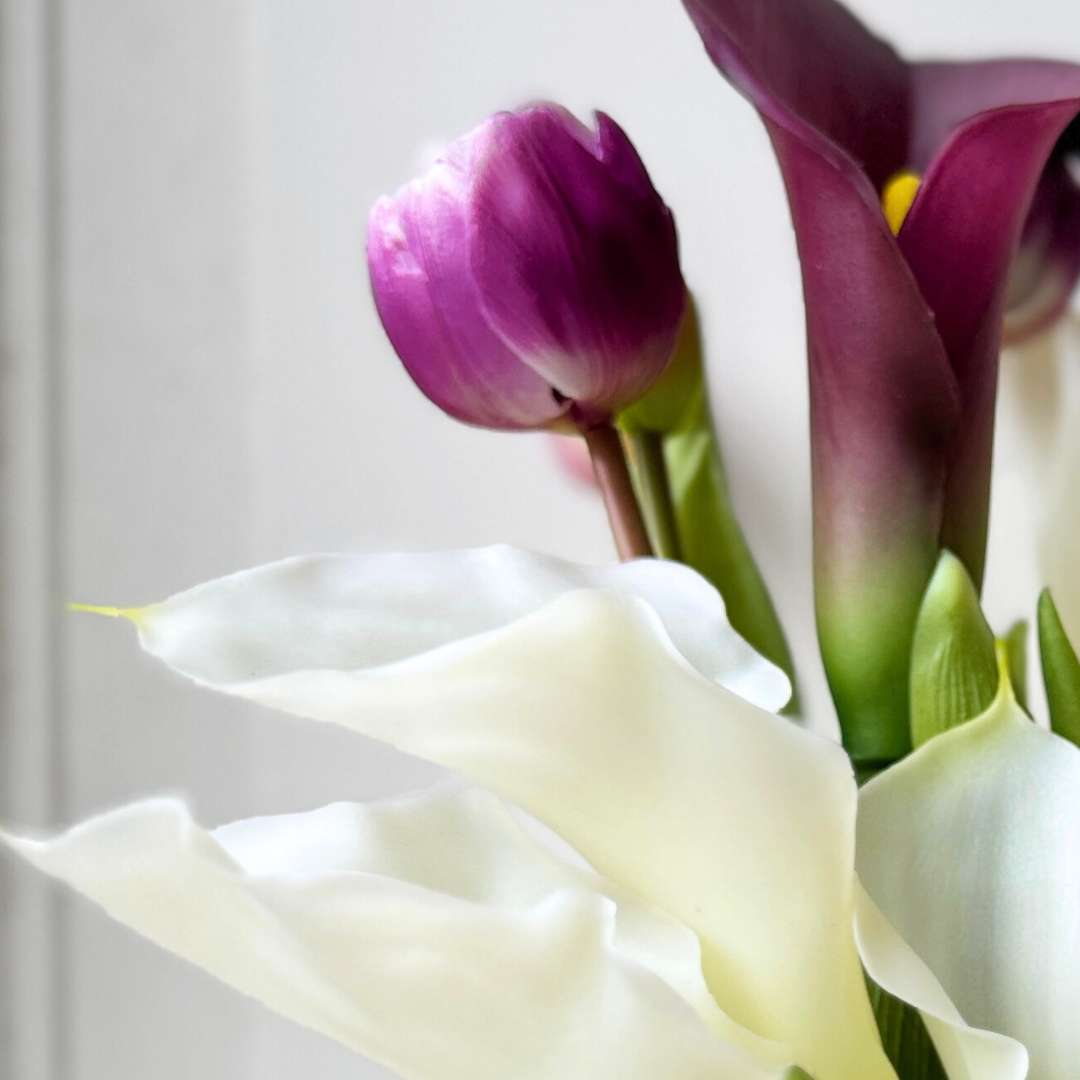 Close up of Realistic artificial flower bridal bouquet featuring white artificial orchids, deep wine artificial calla lilies, white artificial calla lilies, and lavender artificial tulips — from My Faux Florist Canada.