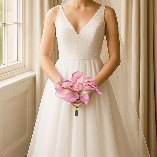 Woman in a white wedding dress holding Real Touch pink calla lilies in a bouquet indoors, by My Faux Florist Canada.