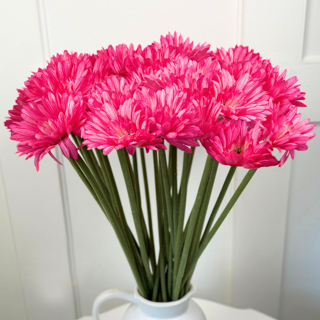 Bouquet of fuchsia fake gerbera daisies in a white vase against a white background from My Faux Florist Canada
