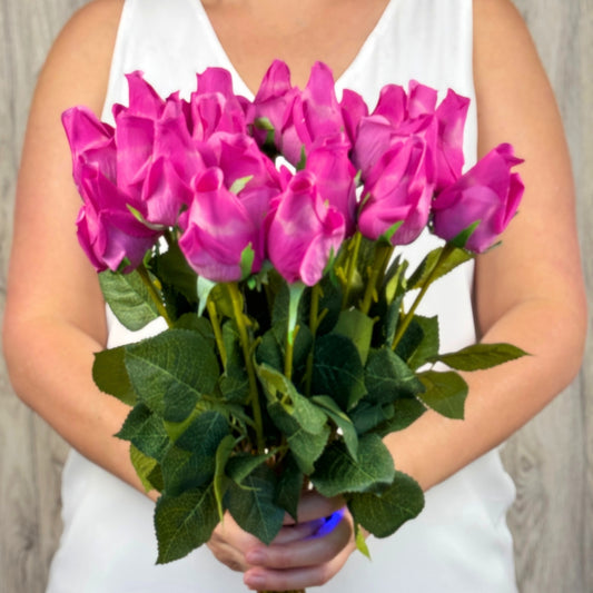 A person holding a bouquet of fuchsia artificial pink rosebuds with green leaves from My Faux Florist Canada