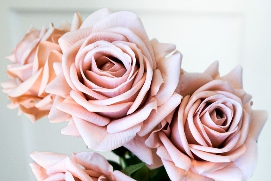 Artificial Flowers Canada. Close-up of faux roses in dusty pink with soft curled petals and a neutral background. Realistic fake flowers by My Faux Florist.