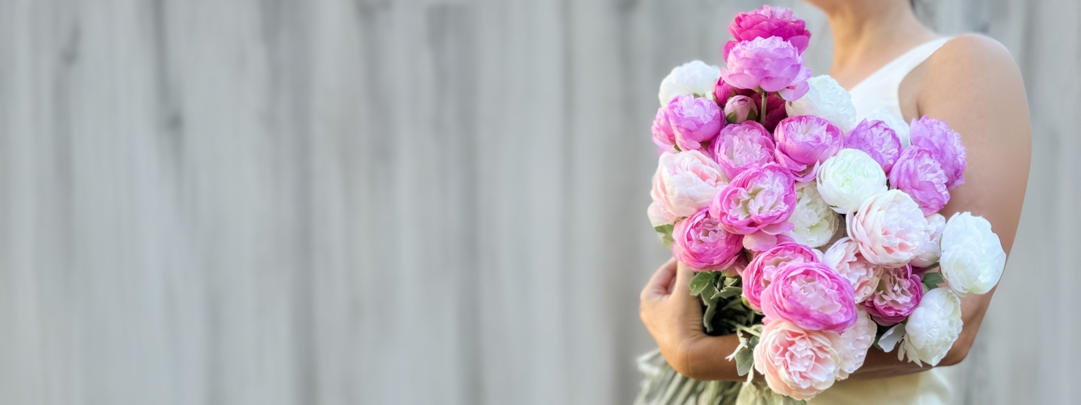 woman in front of grey background holding armful of realistic artificial flowers and faux roses for My Faux Florist Canada