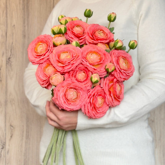 A person holding a bouquet of artificial ranunculus flowers in a coral colour with realistic Real Touch petals, from My Faux Florist artificial flowers Canada.