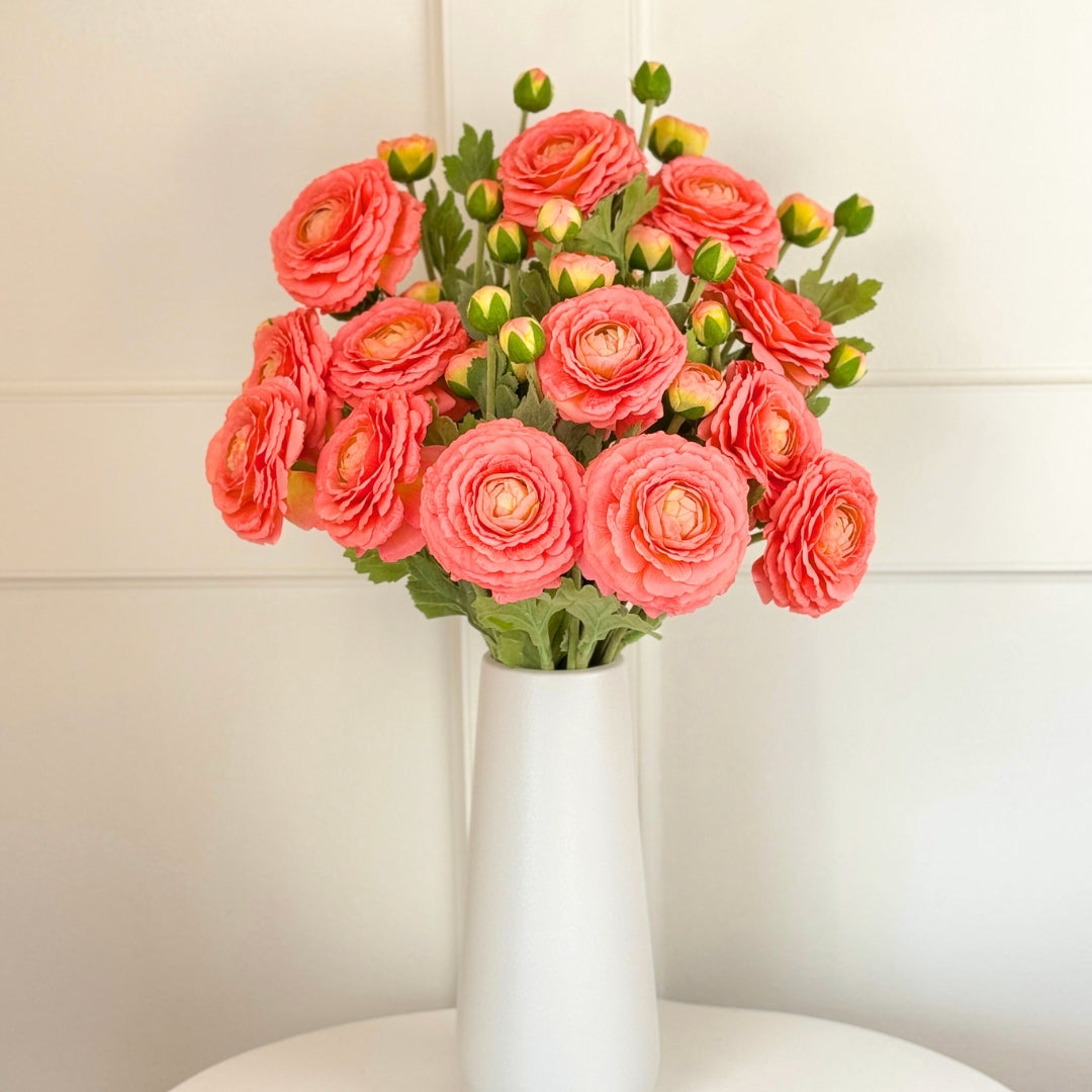 White vase on a white background full of an artificial ranunculus flowers in a coral colour with realistic Real Touch petals, from My Faux Florist artificial flowers Canada.