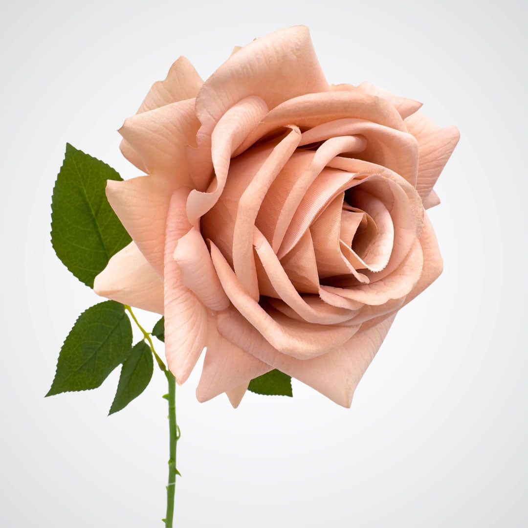 Close-up of a pink faux rose with green leaves on a light gray background, from My Faux Florist Canada.