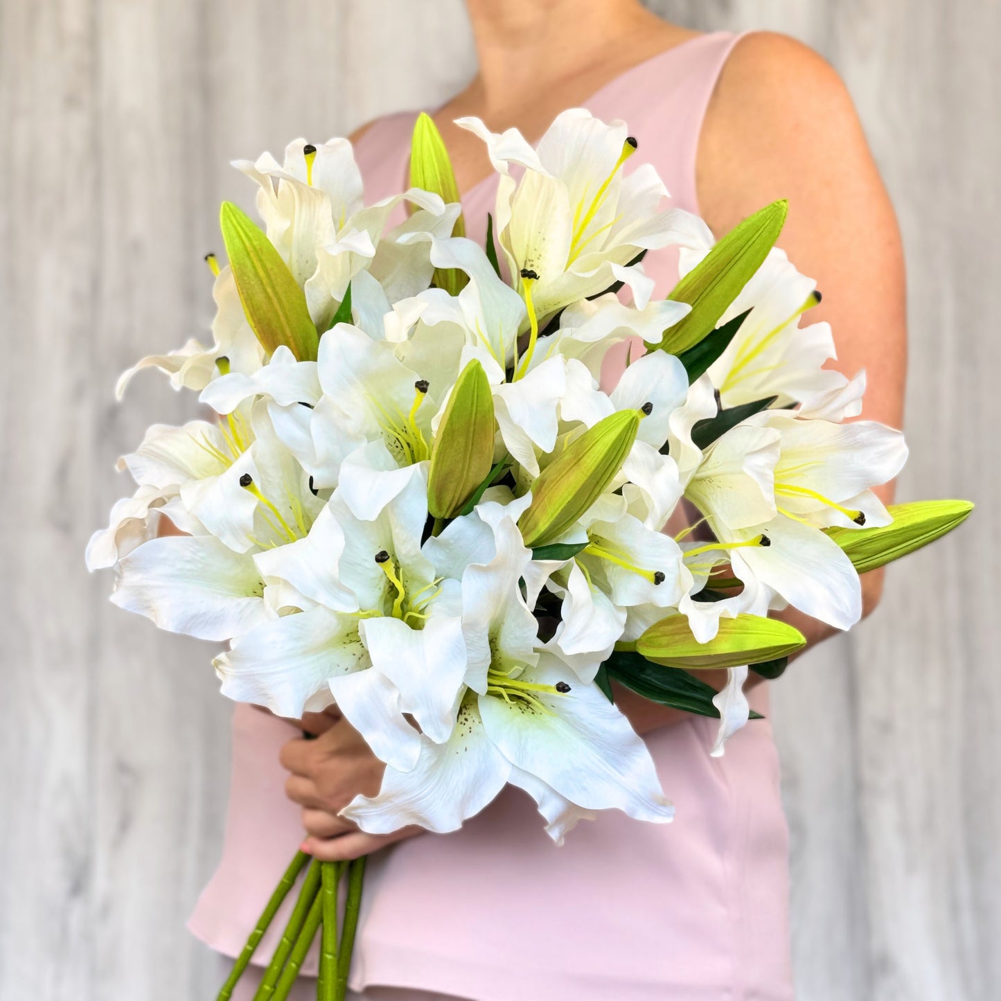 A person holding a bouquet of premium white artificial lilies for Faux Florist Canada.