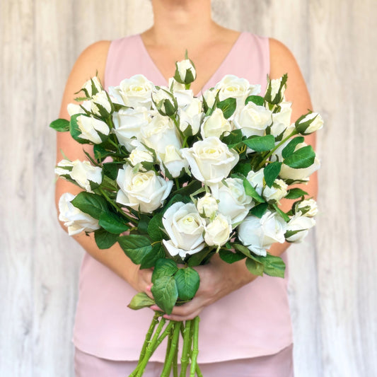 A person holding a bouquet of artificial white roses.