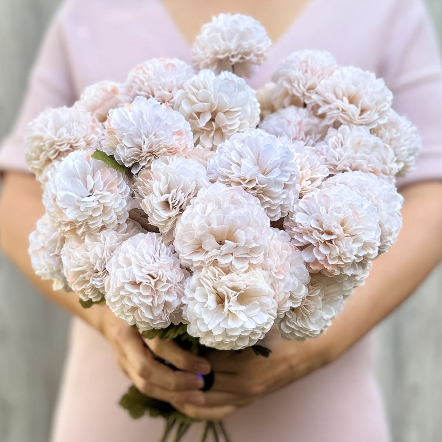 A person holding a bunch of cream-colored artificial chrysanthemum flowers, by My Faux Florist artificial flowers Canada.