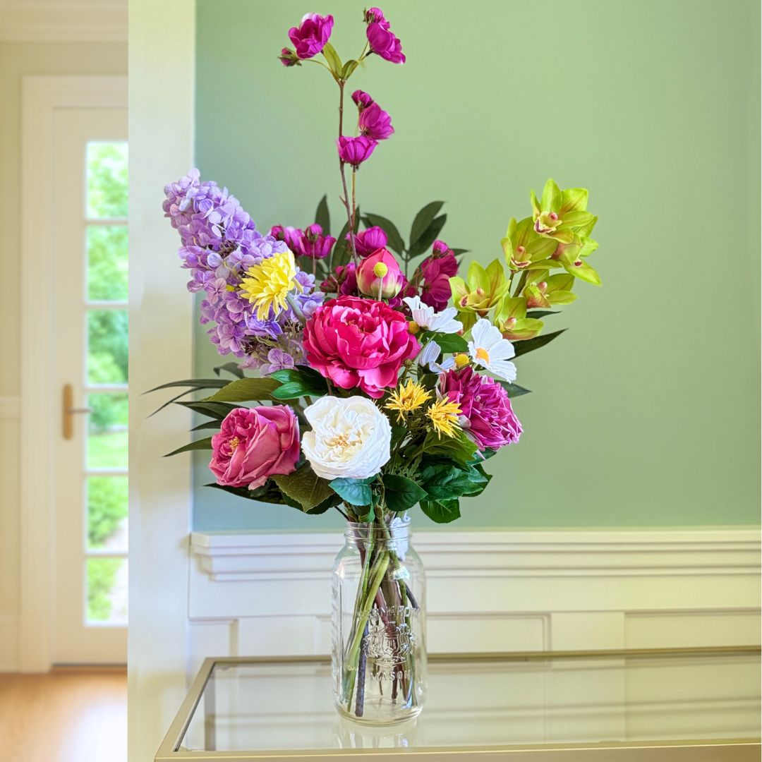 Bouquet of brightly coloured artificial flowers and Real Touch flowers in front of a green wall, by My Faux Florist artificial flowers Canada.
