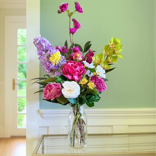 Bouquet of brightly coloured artificial flowers and Real Touch flowers in front of a green wall, by My Faux Florist artificial flowers Canada.