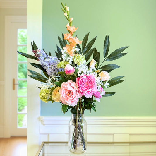 Bouquet of brightly coloured artificial flowers and Real Touch flowers in front of a green wall, by My Faux Florist artificial flowers Canada.
