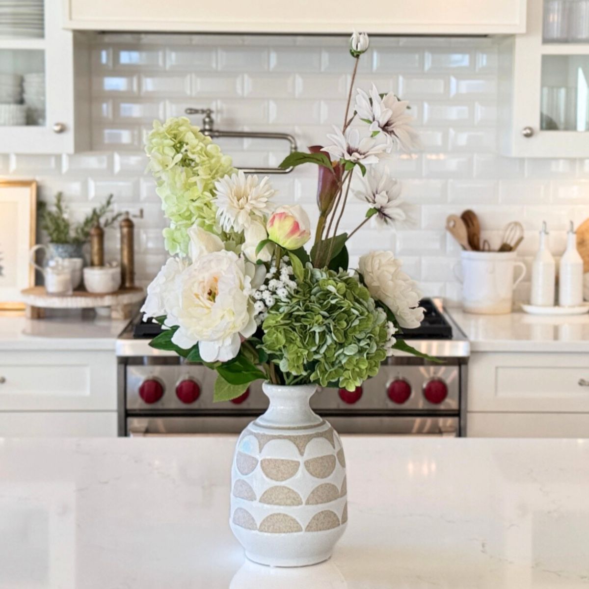 Realistic artificial flower arrangement in a decorative vase on a kitchen counter, for Mt Faux Florist Canada.
