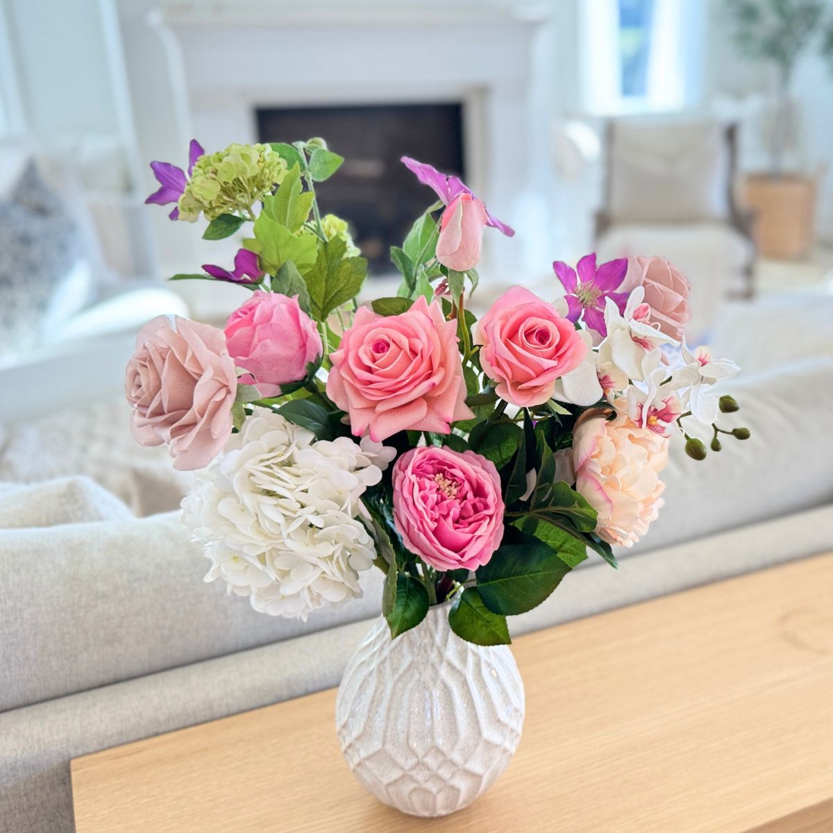 Bouquet of pink and white realistic artificial flowers in a textured white vase on a wooden table. For My Faux Florist Canada.