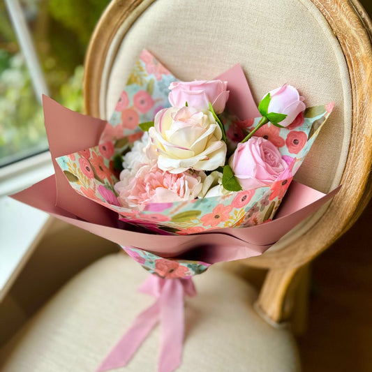 Realistic Real Touch artificial flowers wrapped on a chair featuring blush artificial roses, ivory artificial roses, soft pink artificial peonies, and white artificial dahlias — from My Faux Florist Canada.
