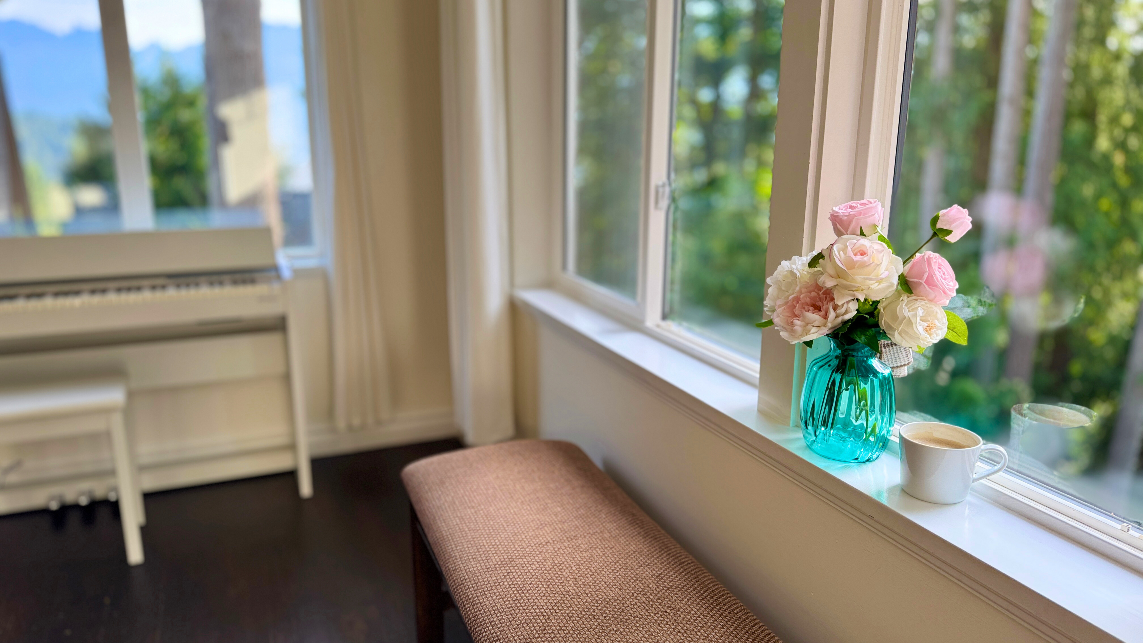 Floral arrangement of realistic artificial flowers in a blue vase on a windowsill with a view of trees outside. in the vase are fake artificial roses, an artificial peony and artificial hydrangea in muted pink and white colours, for My Faux Florist Canada.