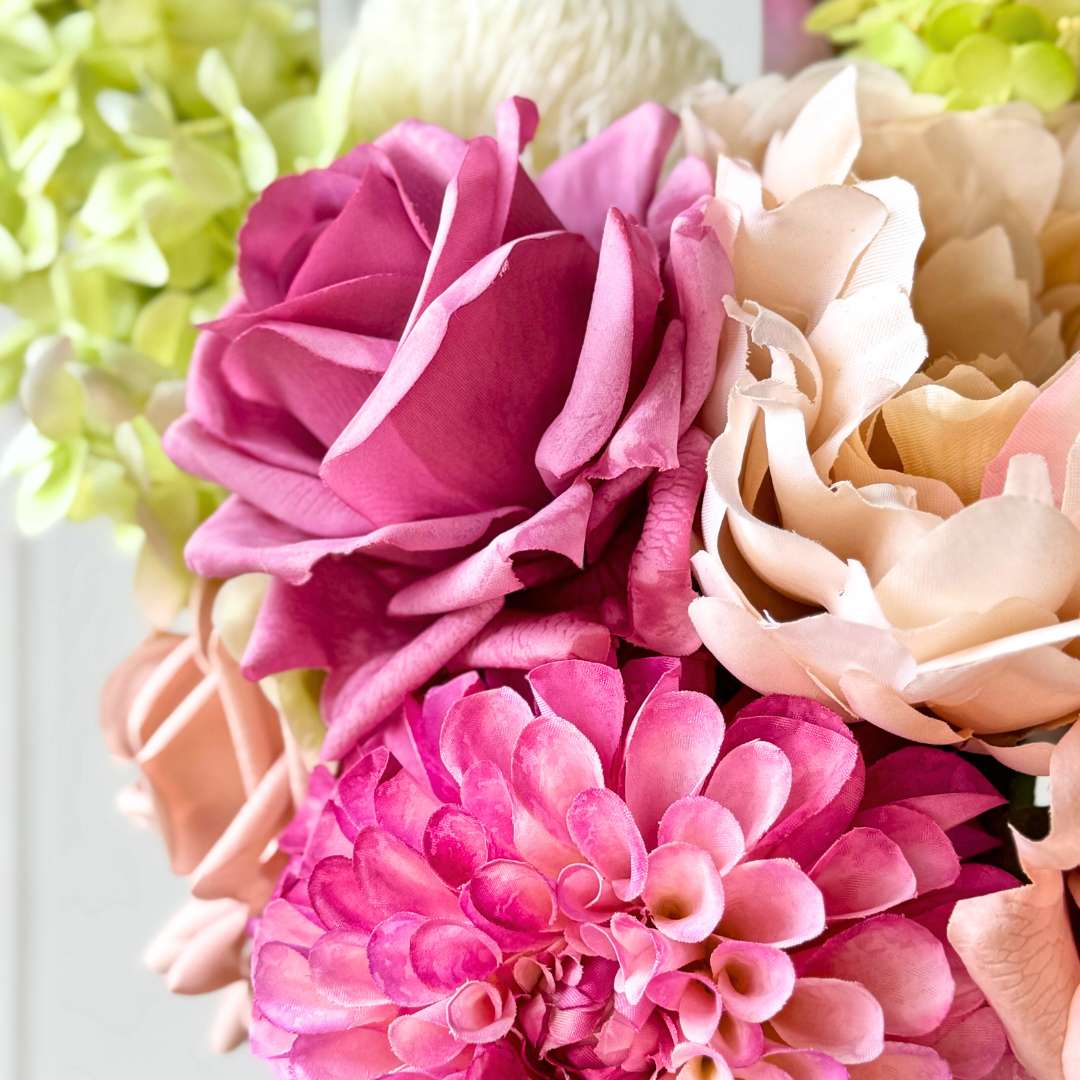 Close up of  a realistic artificial flower bridal bouquet featuring antique cream artificial roses, dusty mauve artificial roses, blush artificial peonies, pink artificial dahlias, pale green artificial hydrangeas, green artificial peonies, and deep wine artificial calla lilies —  Real Touch Flowers from My Faux Florist Canada.