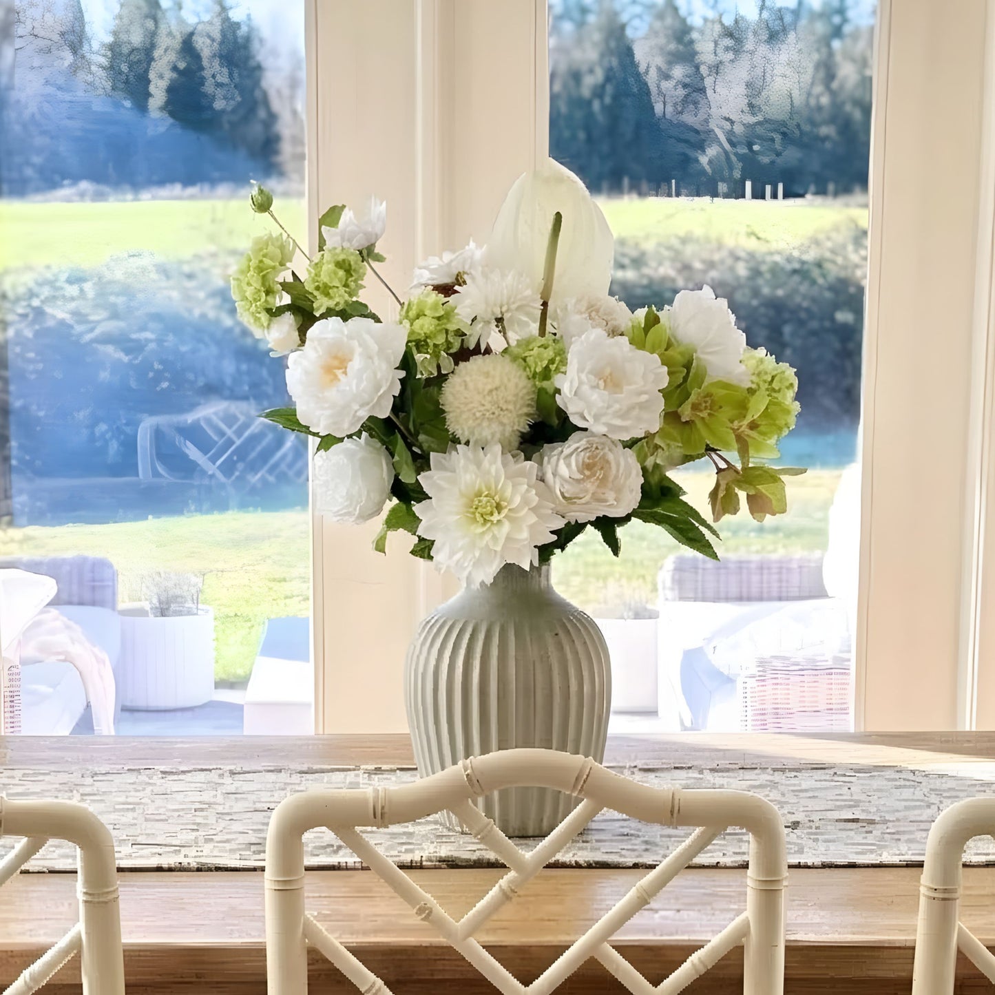Floral arrangement in a vase of realistic artificial flowers, on a windowsill with a view of trees outside. Faux peonies, faux roses, faux hydrangea, and faux orchids in an artificial flower bouquet for My Faux Florist Canada.
