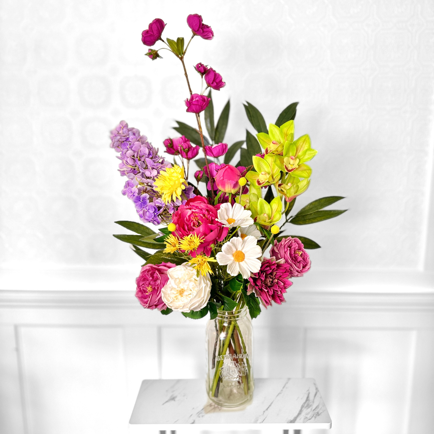 Bouquet of brightly coloured artificial flowers and Real Touch flowers in front of a white wall, by My Faux Florist artificial flowers Canada.
