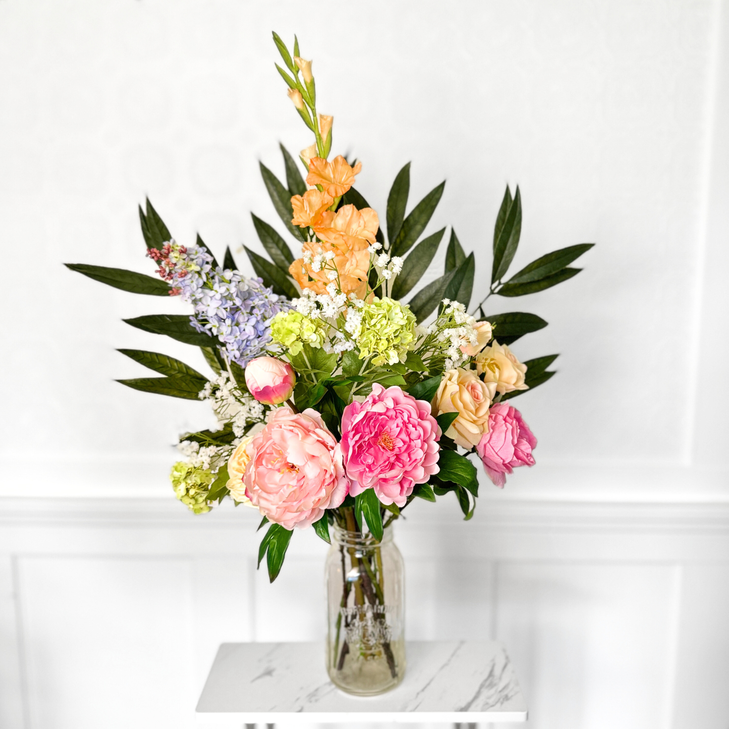 Bouquet of brightly coloured artificial flowers and Real Touch flowers in front of a white wall, by My Faux Florist artificial flowers Canada.