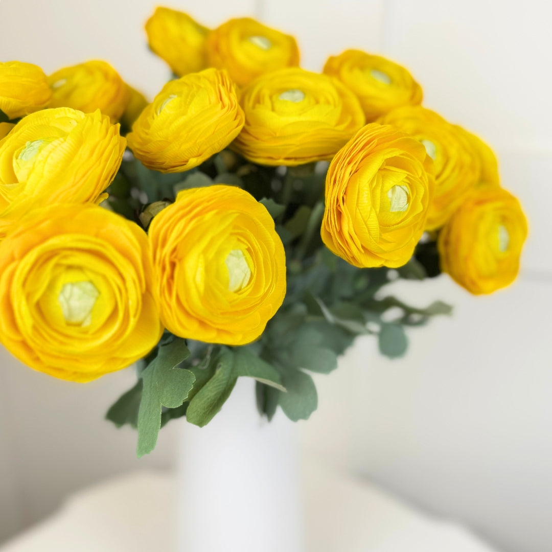 Bouquet vase of yellow faux ranunculus flowers with green leaves on a light background from My Faux Florist Canada