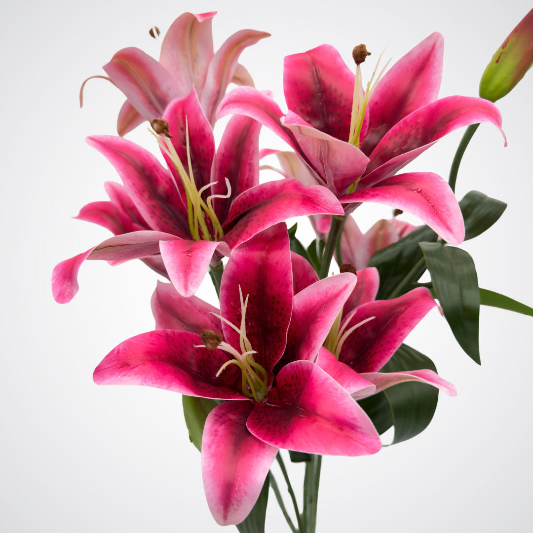 close up view of blooms on premium realistic artificial oriental lilies in fuchsia color with green leaves by My Faux Florist.