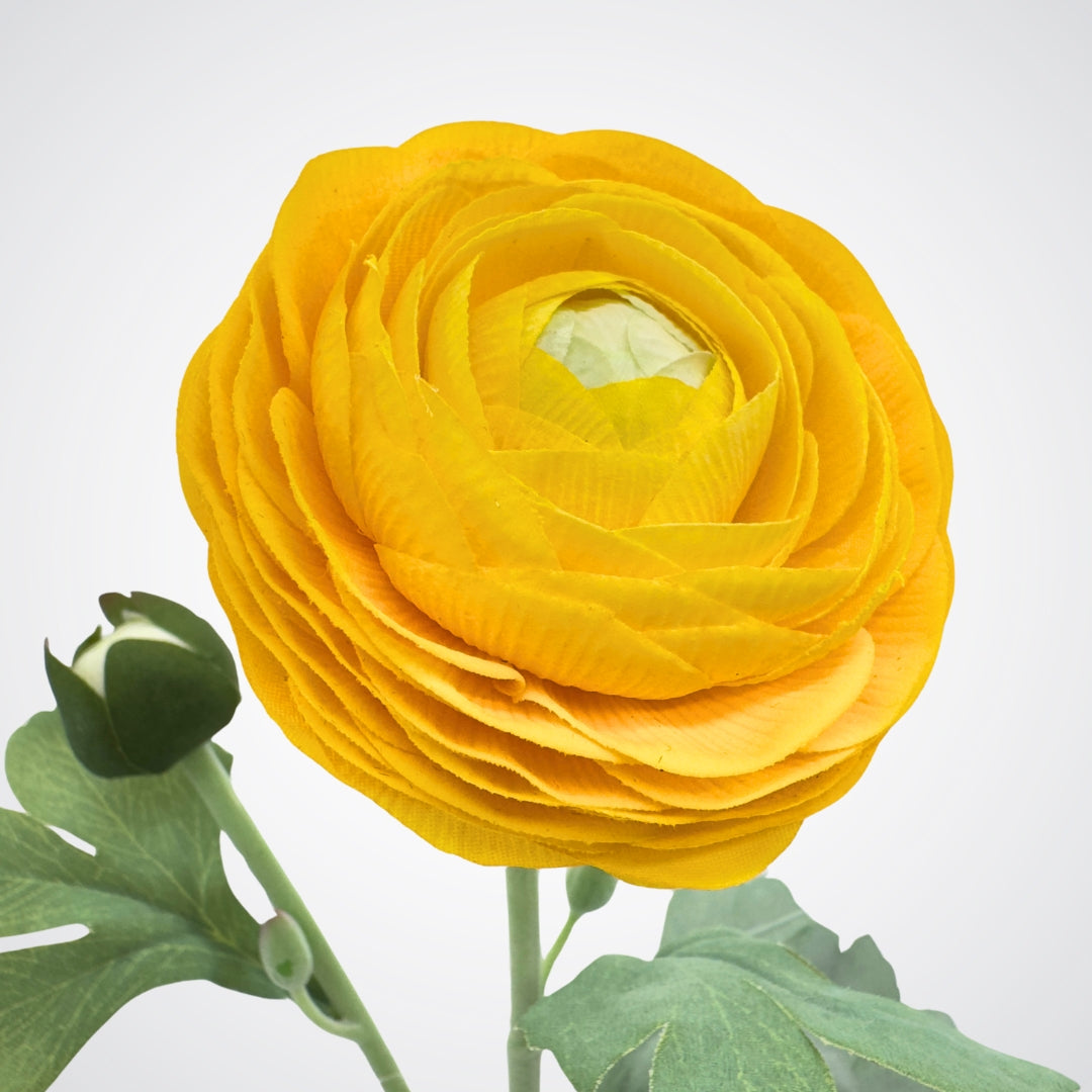 Yellow faux ranunculus flower with green leaves on a white background from My Faux Florist Canada