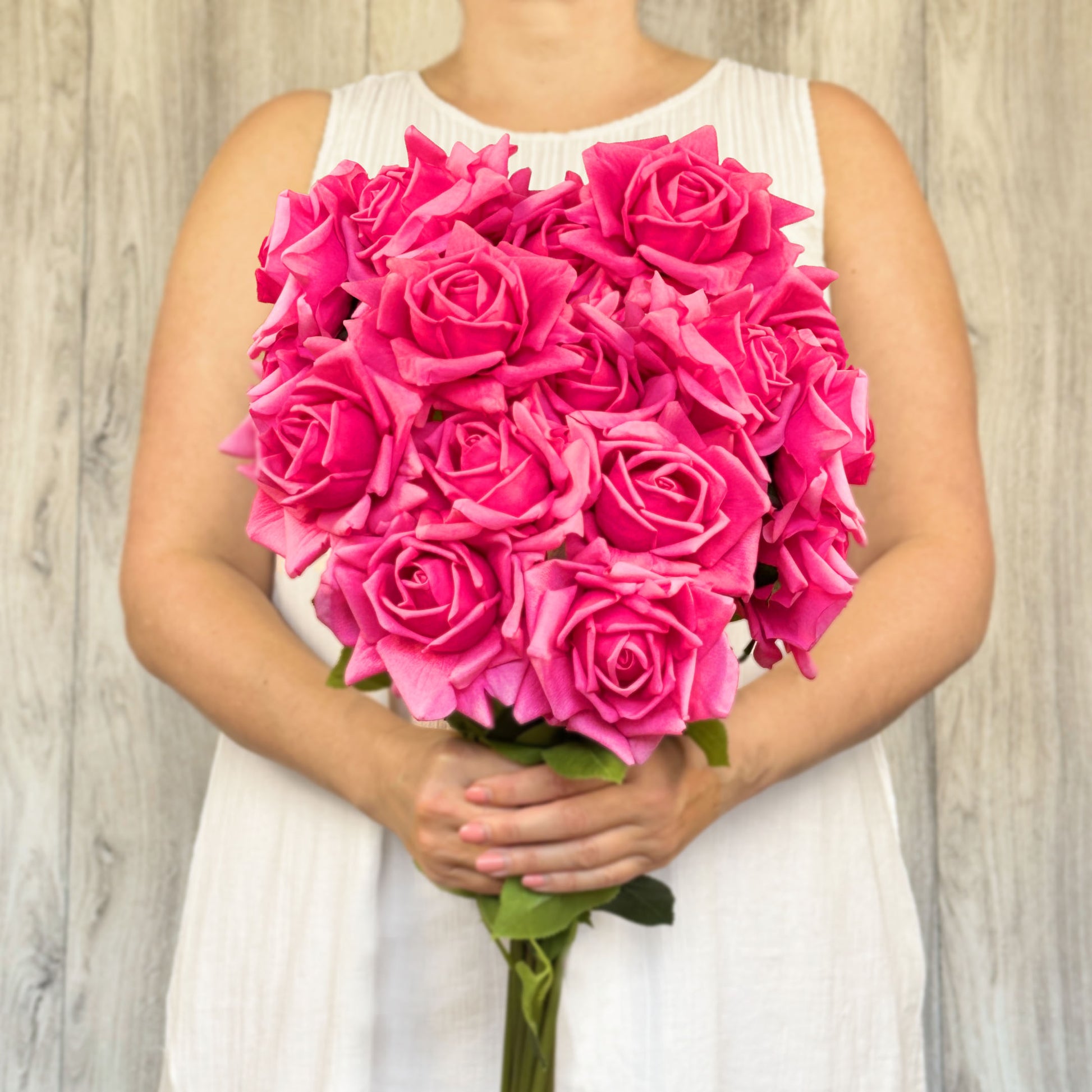 A person holding a bouquet of fuschia realistic artificial pink tea roses by My Faux Florist Canada