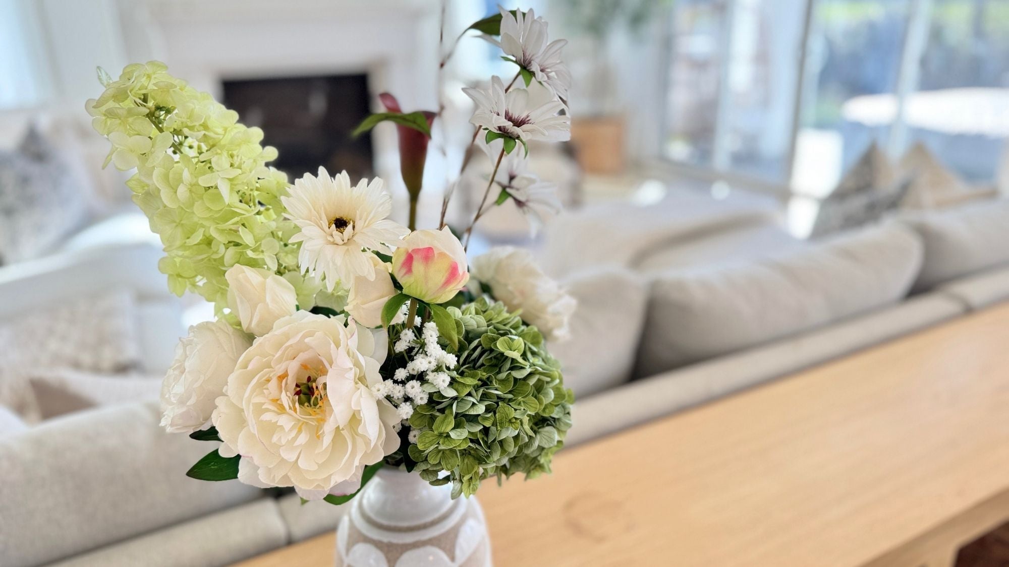 Floral arrangement of artificial flowers in a vase on a coffee table with a living room background, for My Faux Florist Canada