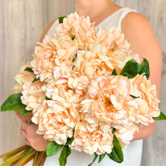 Large bouquet of Artificial Flowers.  Person holding armful of realistic champagne-peach colored fake peonies.