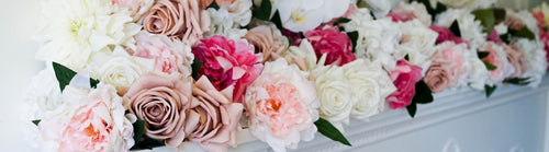 Decorative arrangement of artificial flowers including pink fake roses, white fake roses, and pink fake peonies on a white surface and Real Touch flowers by My Faux Florist artificial flowers Canada.
