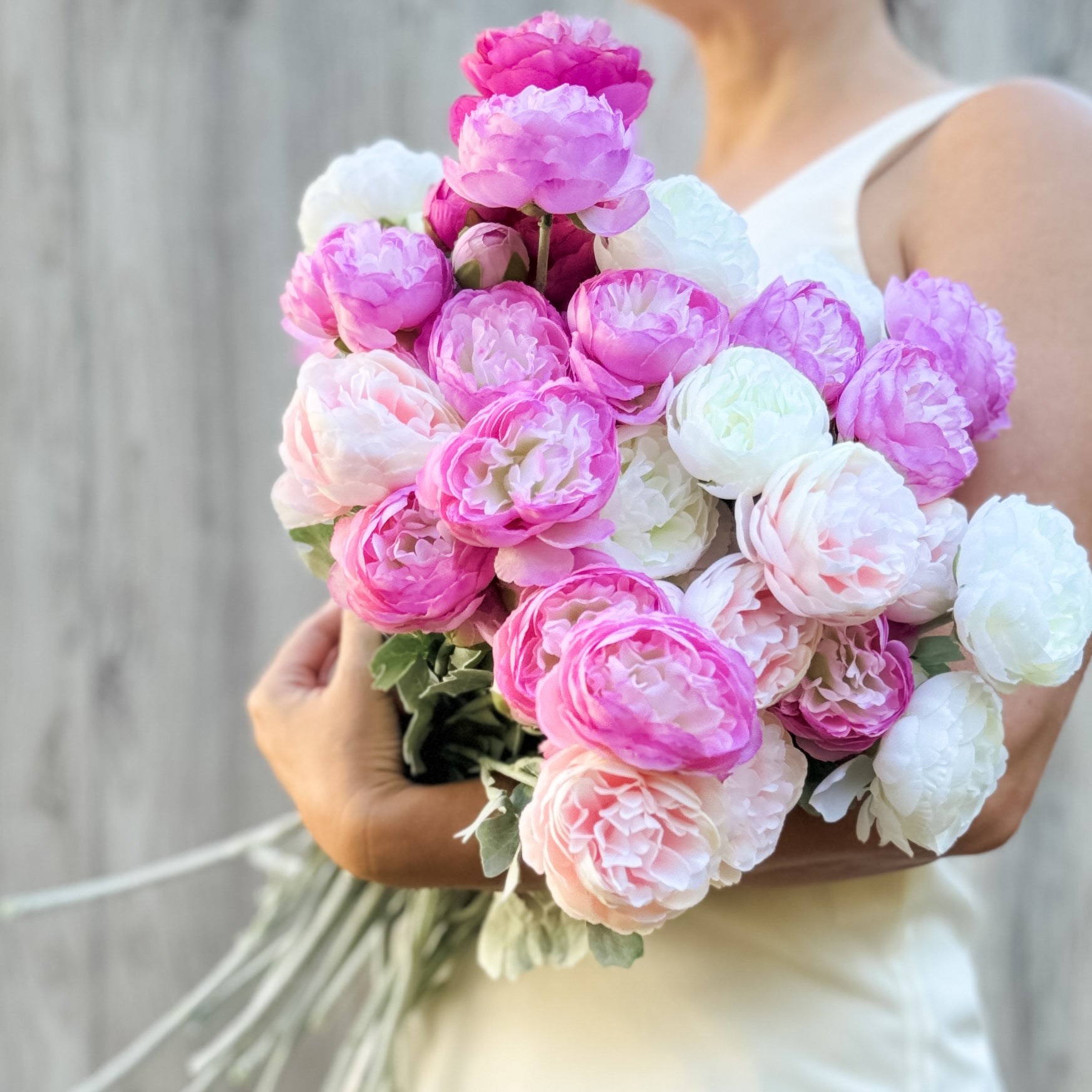 A person holding a large bouquet of artificial roses in shades of pink, white, and green, by My Faux Florist artificial flowers Canada.