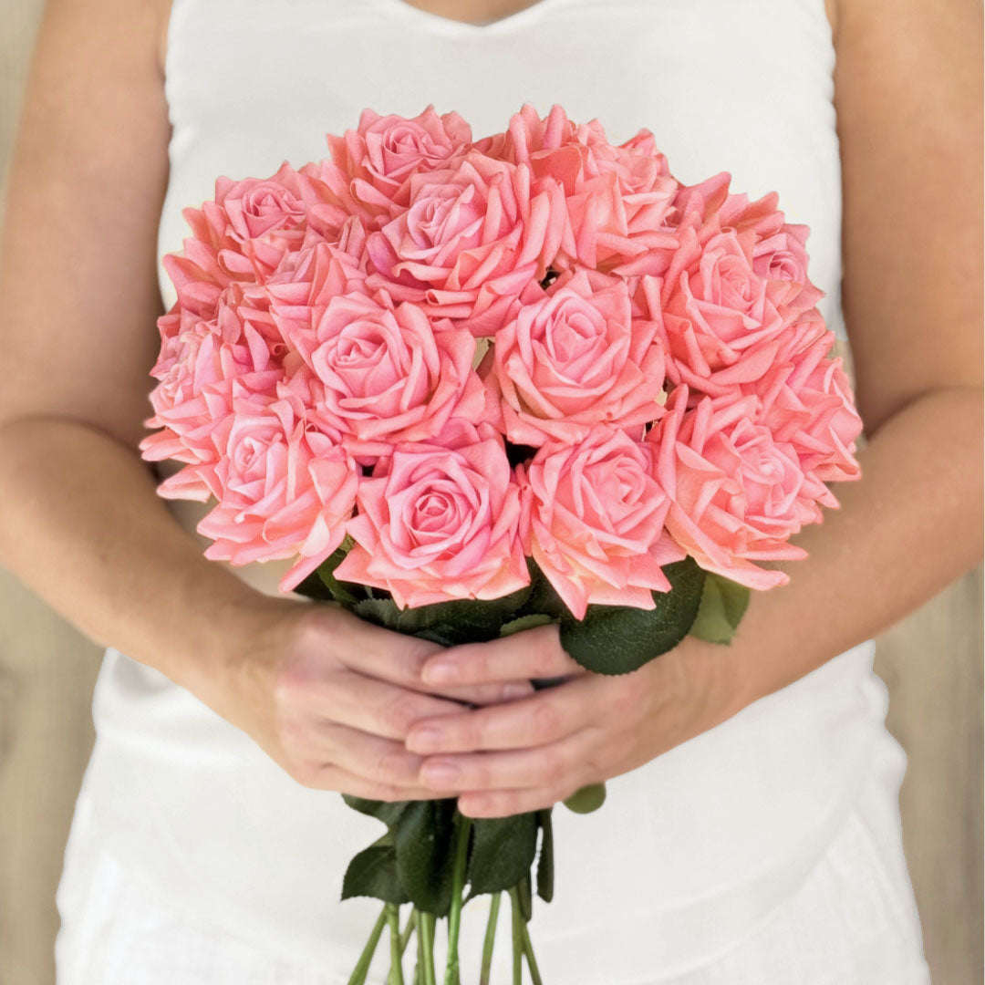 A person holding a bouquet of coral pink artificial tea roses that are Real Touch realistic looking fake roses by My Faux Florist Canada