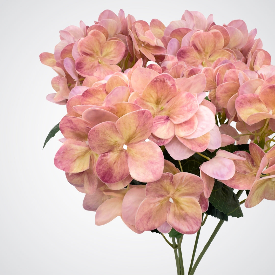 Close up view of a medium pink artificial hydrangea bush with subtle purple undertones and realistic Real Touch veining. Realistic fake flowers by  My Faux Florist Canada