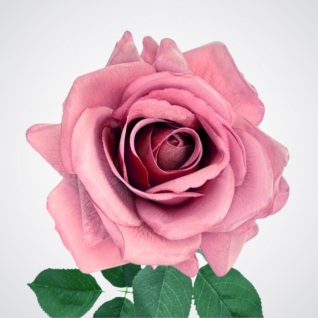 Close-up of a pink fake rose with green leaves on a light background, from My Faux Florist Canada.