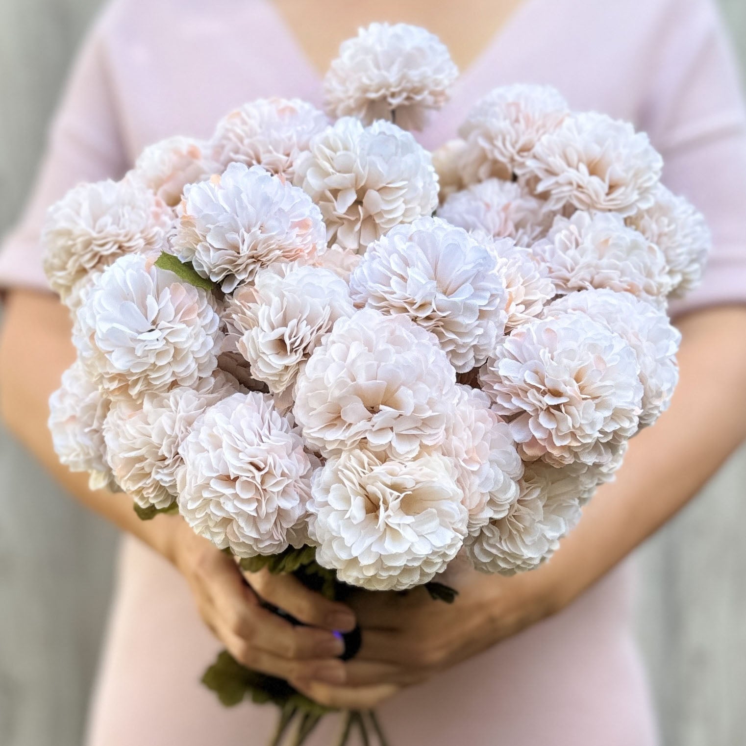 A person holding a bunch of cream-colored artificial chrysanthemum flowers, by My Faux Florist artificial flowers Canada.