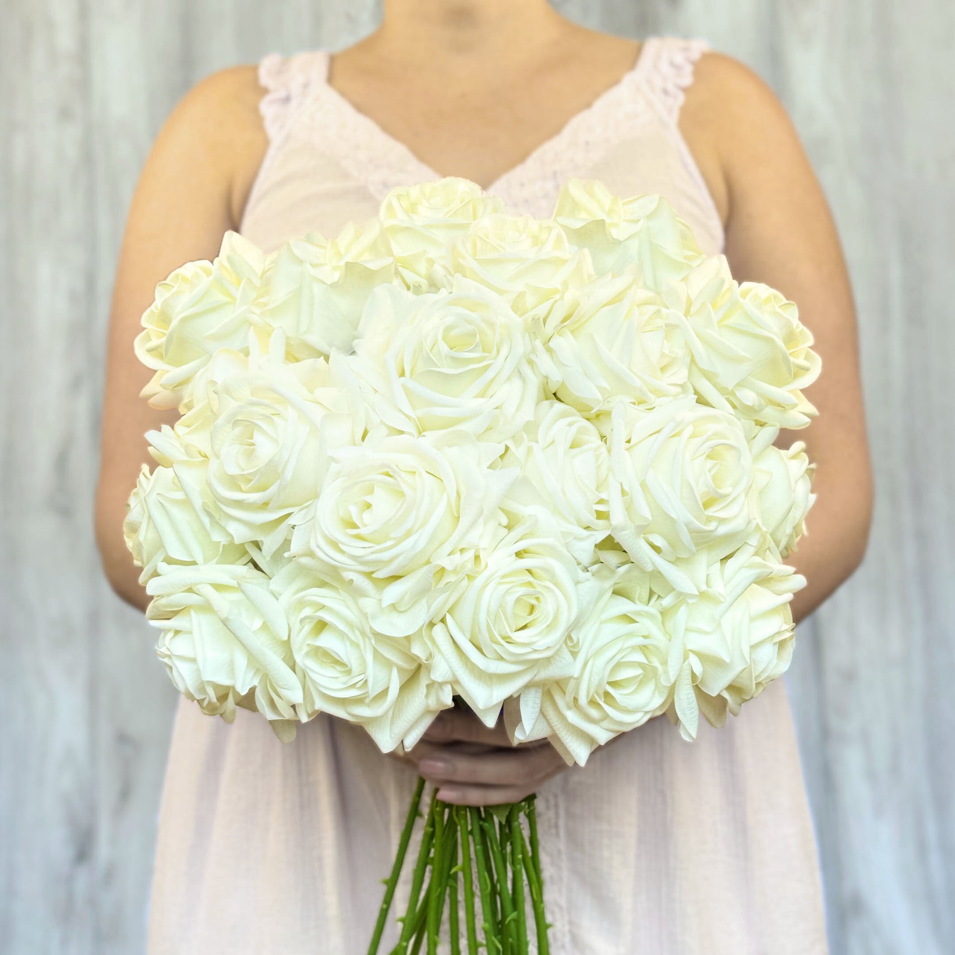 person holding a bouquet of whit realistic fake roses, against a grey background, for My Faux Florist Canada.