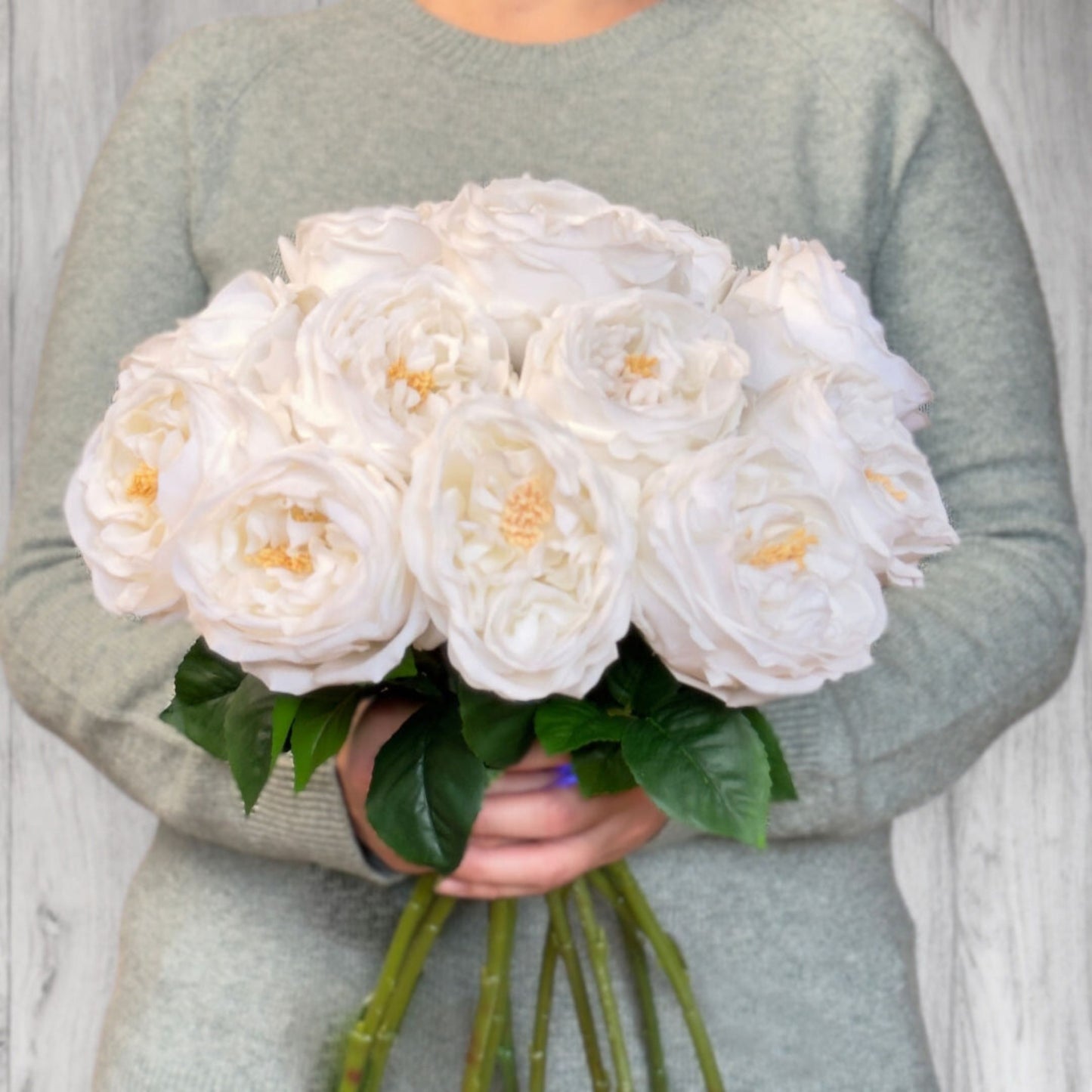 A person holding a bouquet of white  Austin rose style realistic artificial roses with realistic Real Touch petals, from My Faux Florist artificial flowers Canada.
