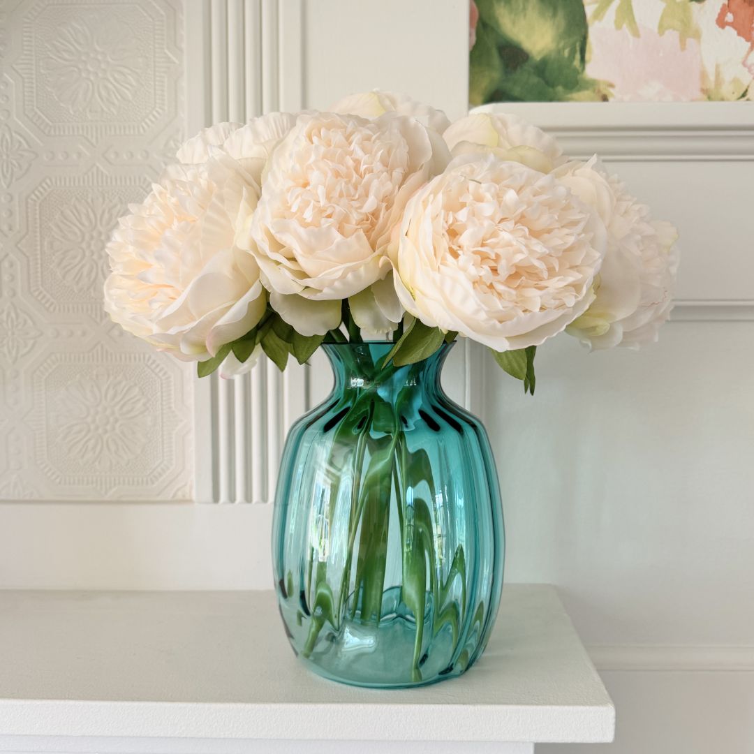 Green vase of white faux peonies on a mantel by My Faux Florist artificial flowers Canada.