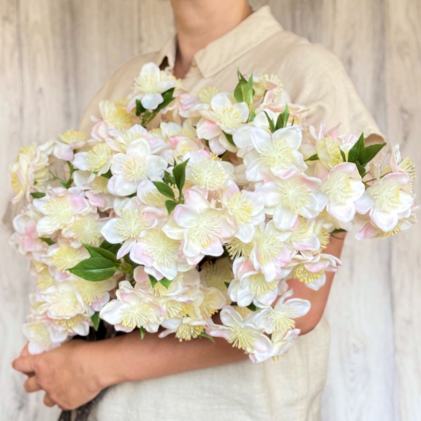 Person holding a large bouquet in her arms of artificial apple blossom branch with ivory white blooms and soft yellow pollen tips.  The petals are Real Touch and detailed, by My Faux Florist Canada