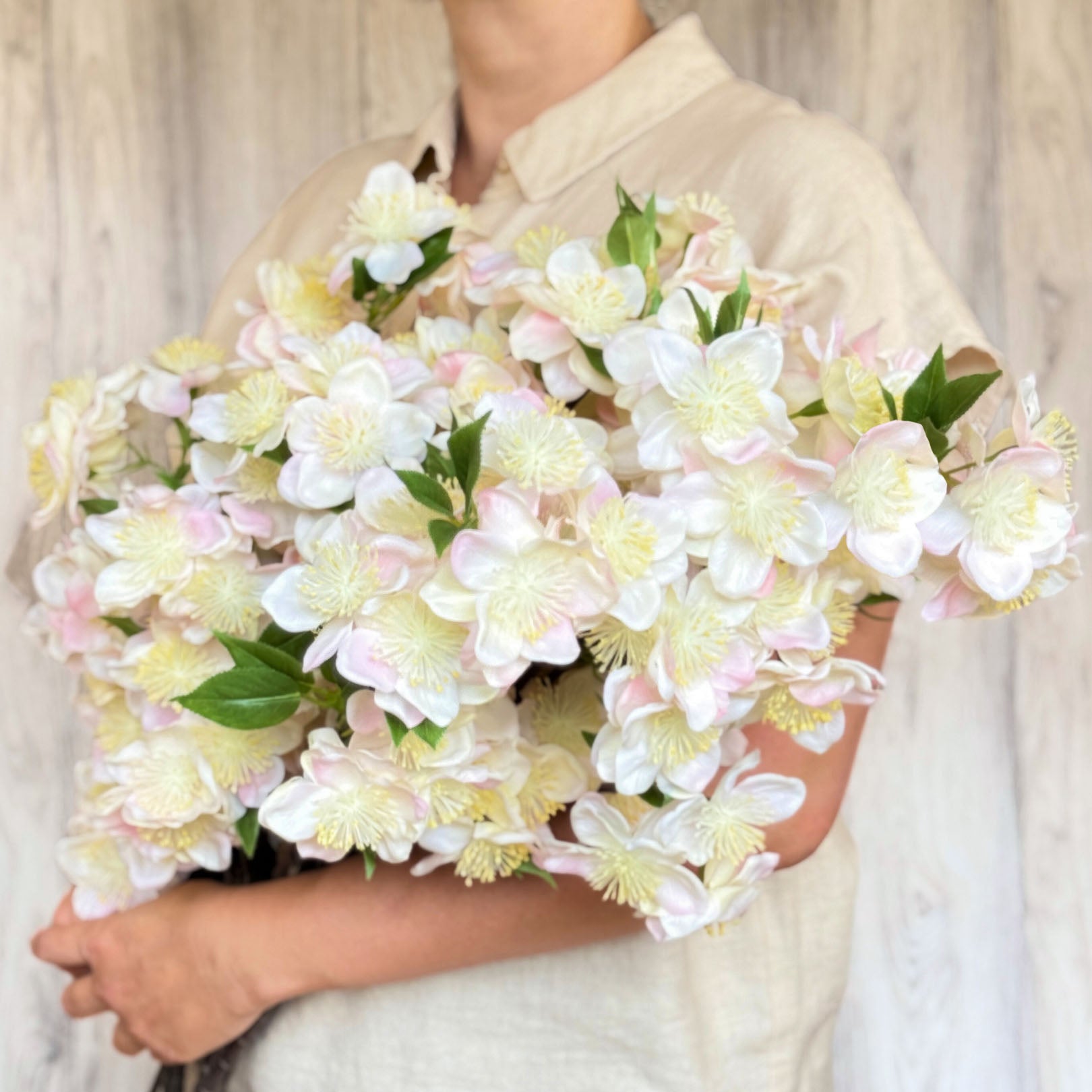 Person holding a large bouquet in her arms of artificial apple blossom branch with ivory white blooms and soft yellow pollen tips.  The petals are Real Touch and detailed, by My Faux Florist Canada