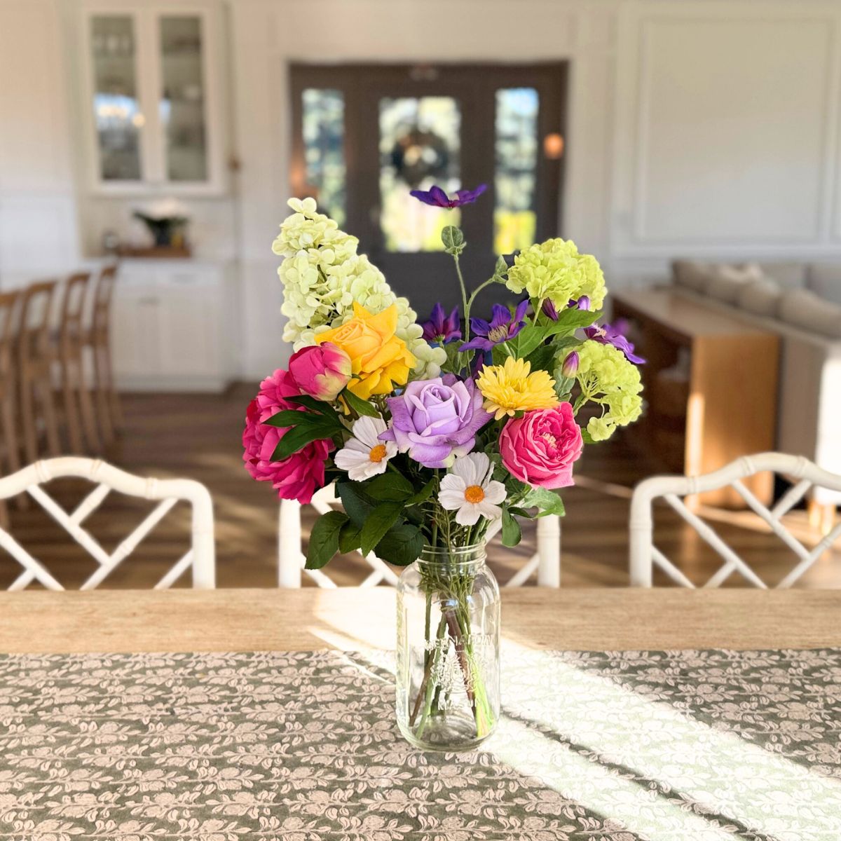 Colorful bouquet of realistic artificial flowers in a vase on a dining table with a kitchen in the background  for My Faux Florist Canada