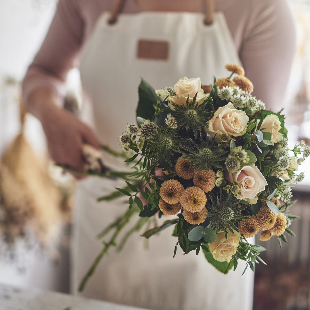 person trimming the ends of a fake flower bouquet