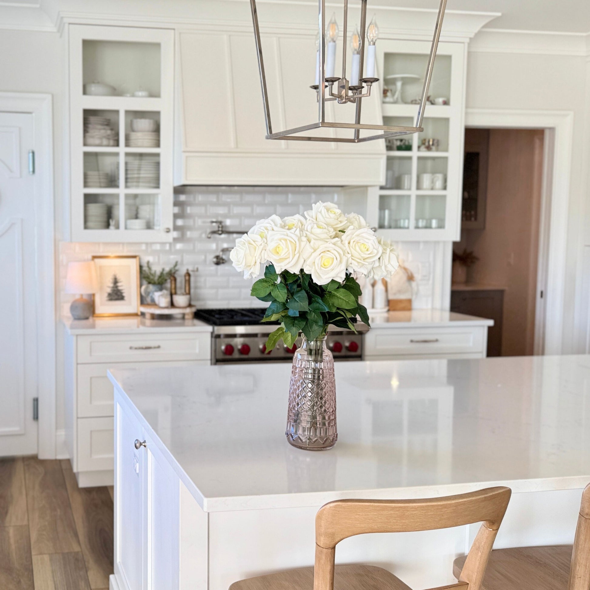 Modern kitchen with white countertops, cabinets, and a vase of white realistic artificial roses on the island - for My Faux Florist Canada.