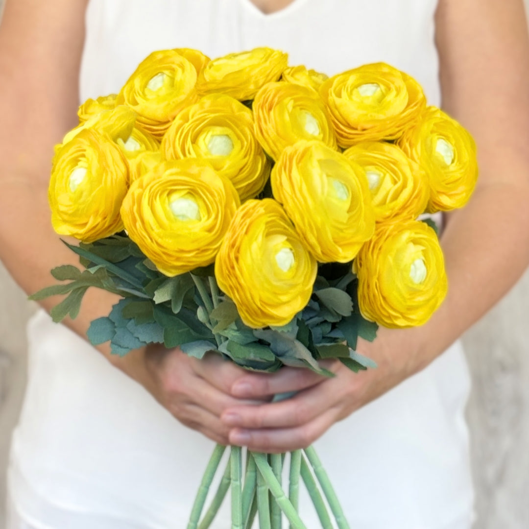 A person holding a bouquet of yellow artificial ranunculus flowers from My Faux Florist Canada