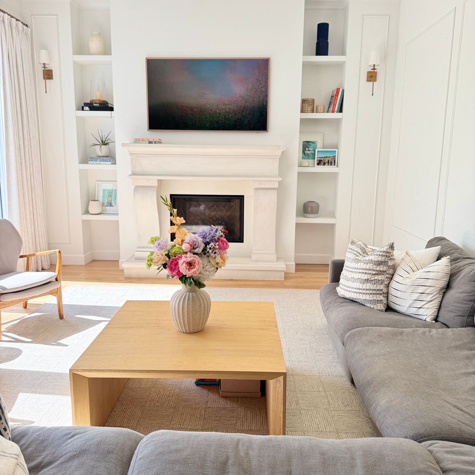 Living room with gray sofa, wooden coffee table, and realistic artificial floral arrangement. Faux peonies, faux roses, faux hydrangea  for My Faux Florist Canada.