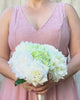 Bridesmaid holding a realistic artificial flower bouquet featuring white artificial roses, white artificial dahlias, and pale green artificial hydrangeas — from My Faux Florist Canada.