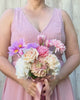 Bridesmaid holding a realistic artificial flower bouquet featuring pink artificial tulips, champagne artificial tea roses, blush artificial peonies, white artificial hydrangeas, pink artificial dahlias, and lavender artificial cosmos tied with a satin ribbon — from My Faux Florist Canada.